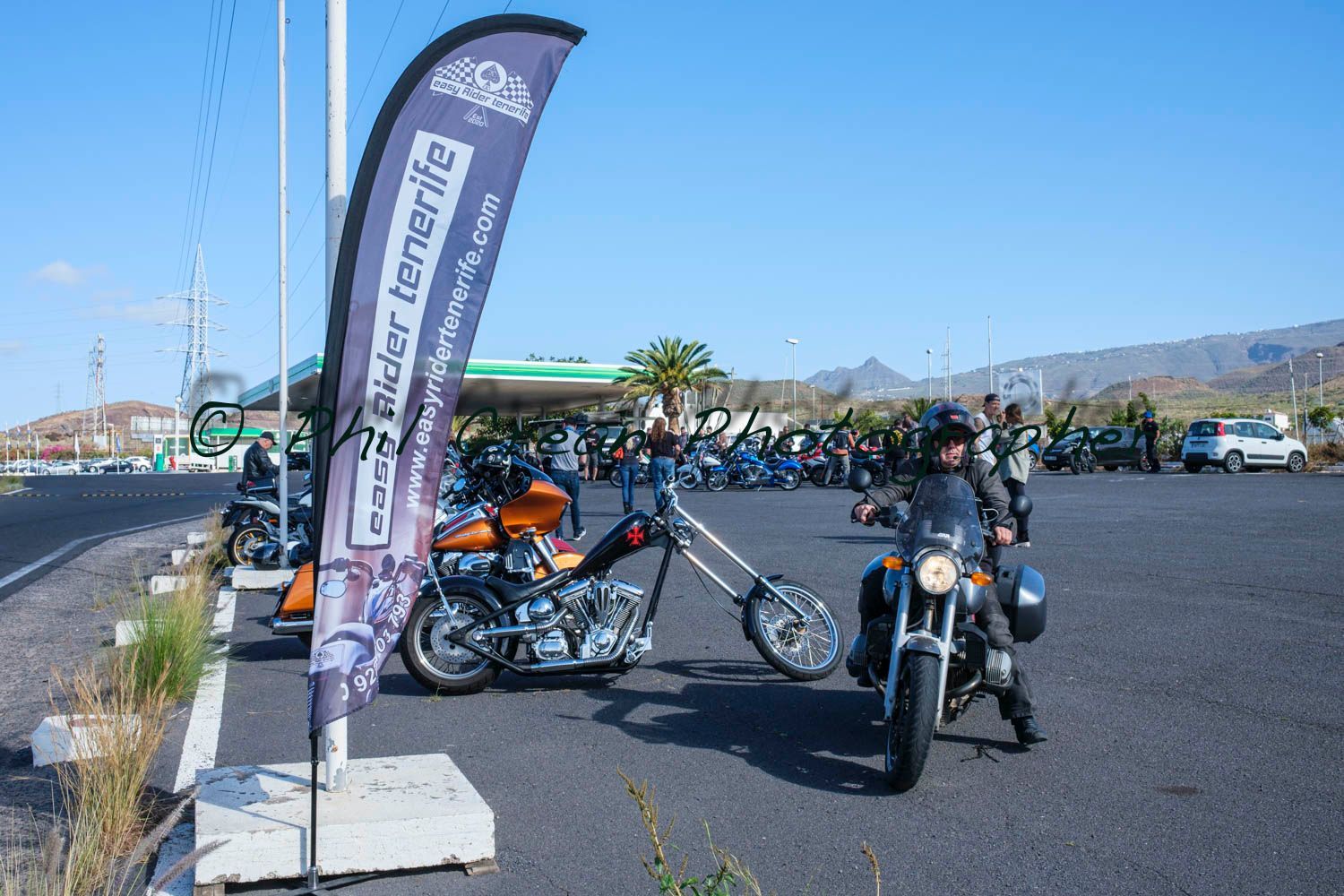 A man is standing next to a motorcycle in a parking lot.