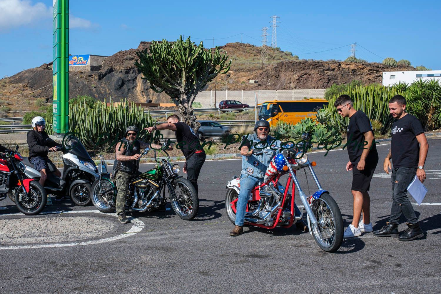 A group of men are standing around motorcycles in a parking lot.