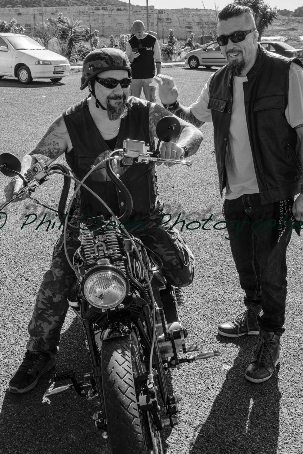 Two men are standing next to a motorcycle in a parking lot.
