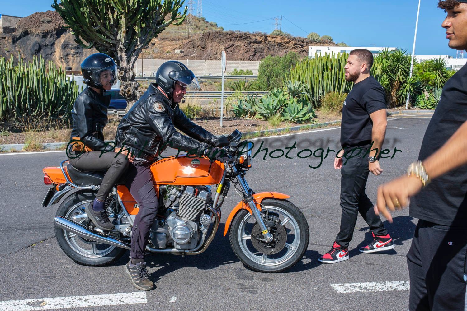 A man and a woman are riding an orange motorcycle