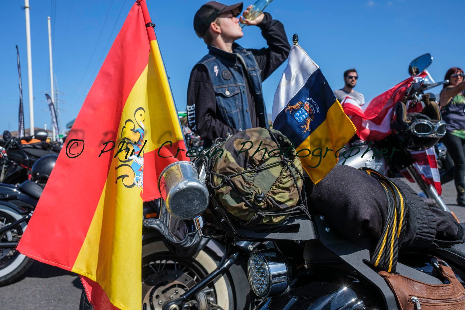 A man is drinking from a bottle while sitting on a motorcycle.