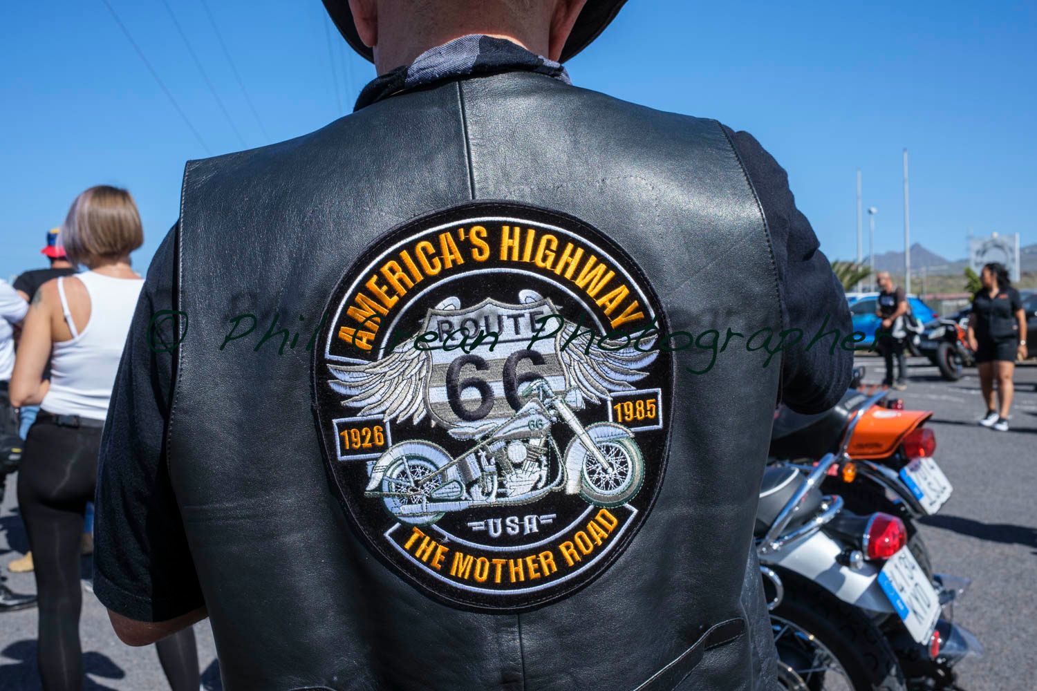 A man wearing a leather vest that says america 's highway on it