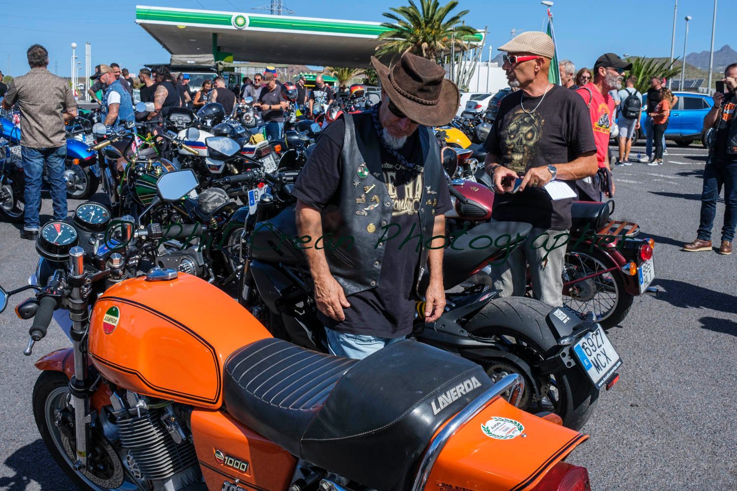 Two men are sitting on a motorcycle in a parking lot.