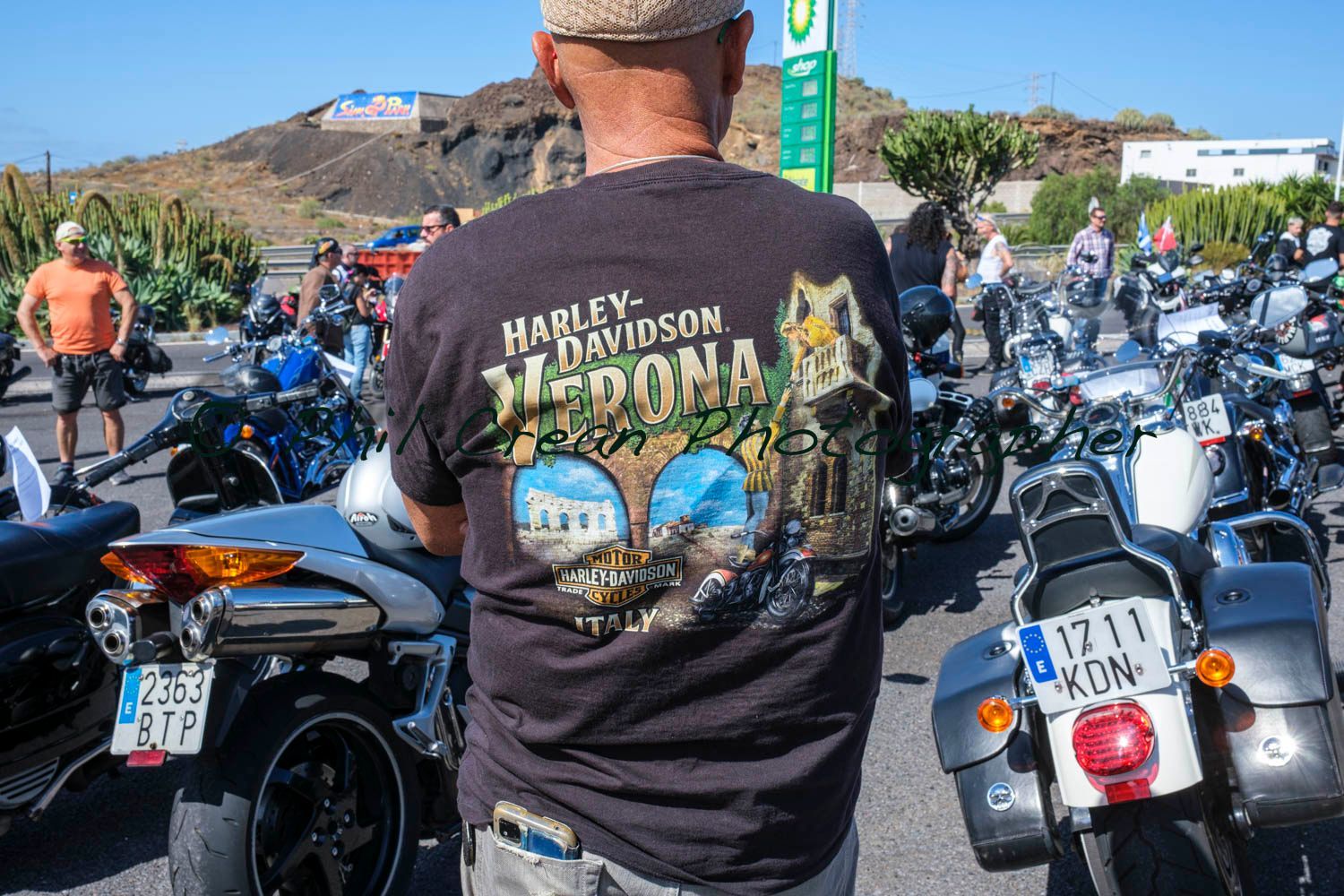 A man wearing a harley davidson shirt is standing in front of a row of motorcycles.