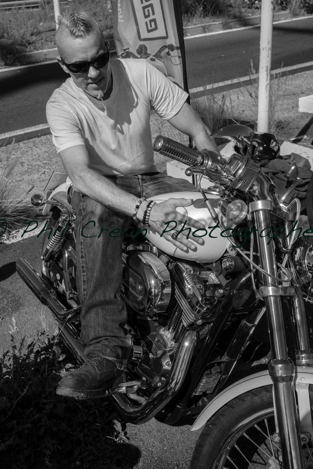 A man is sitting on a motorcycle in a black and white photo.