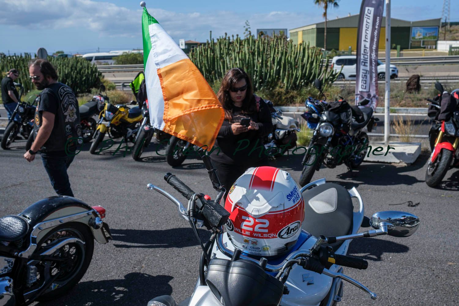 A woman is standing next to a motorcycle holding an irish flag.