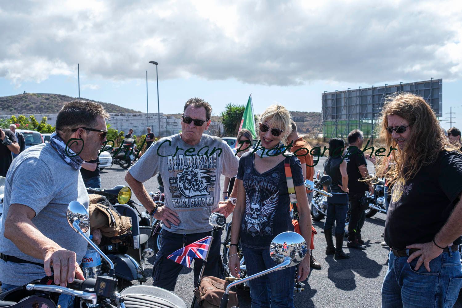 A group of people are standing around motorcycles in a parking lot.