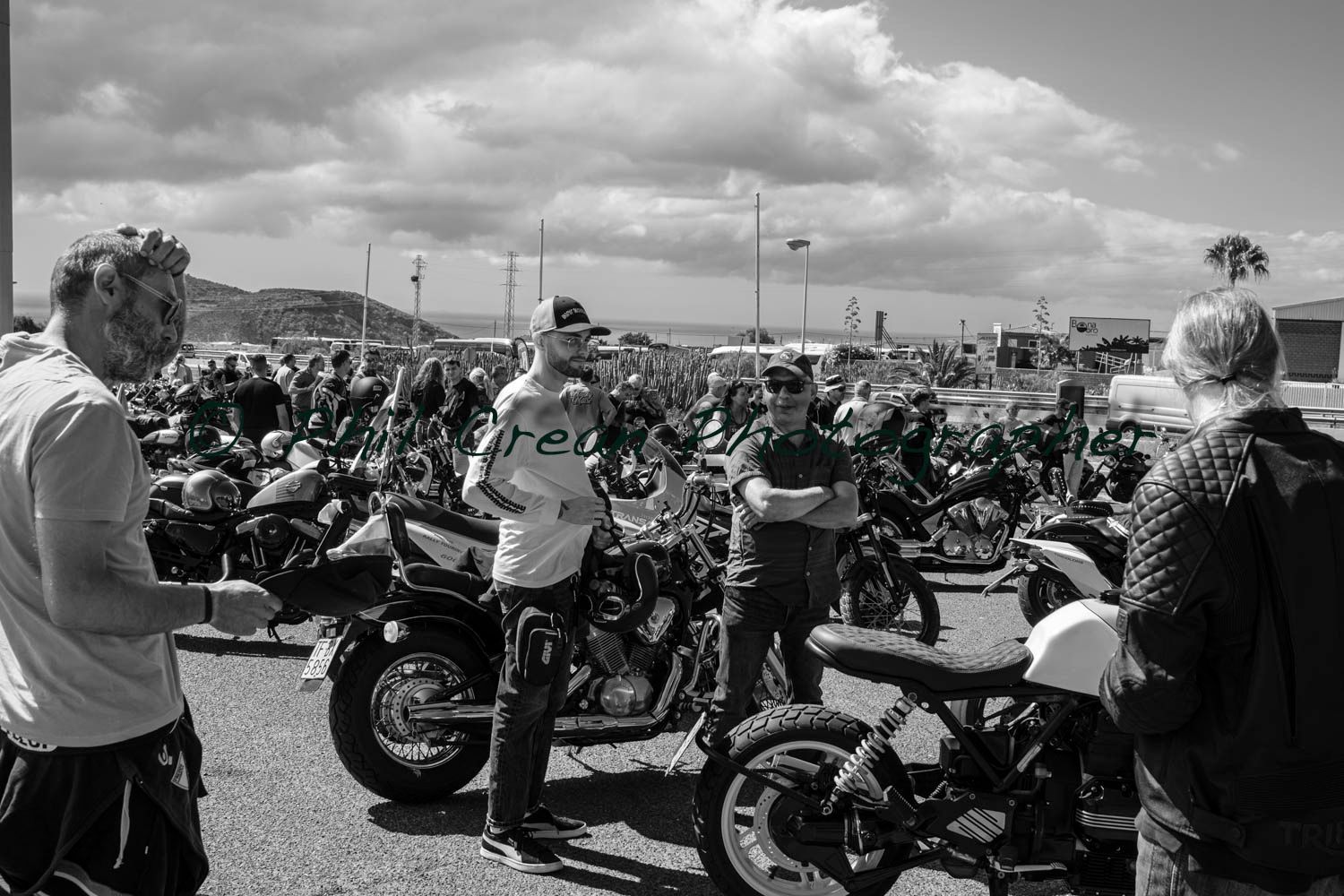 A black and white photo of a group of people standing around motorcycles.