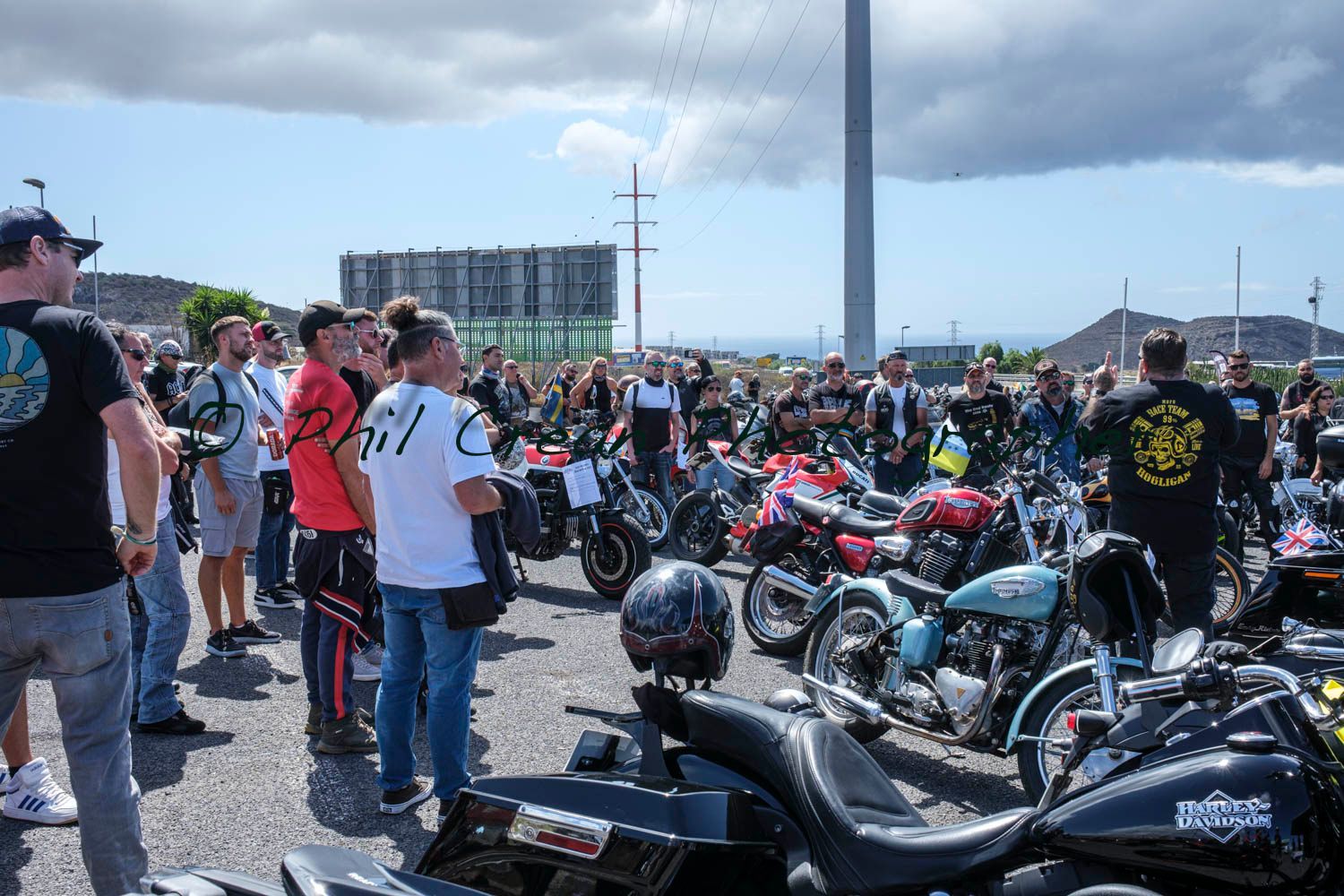 A group of people are standing in front of a row of motorcycles.