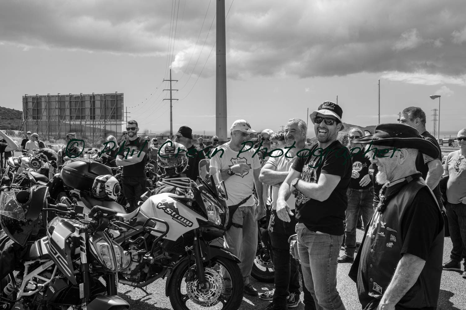 A black and white photo of a group of people standing around motorcycles.