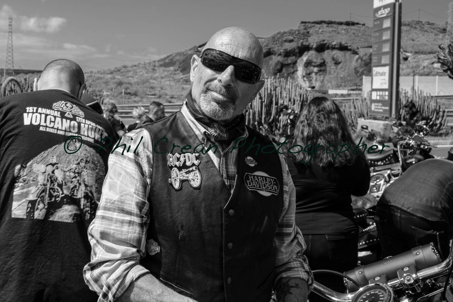 A man wearing sunglasses is standing next to a motorcycle in a black and white photo.