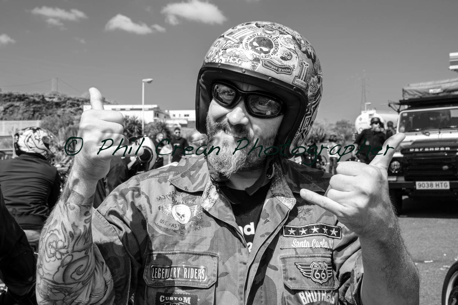 A man wearing a helmet and sunglasses is giving a thumbs up sign.
