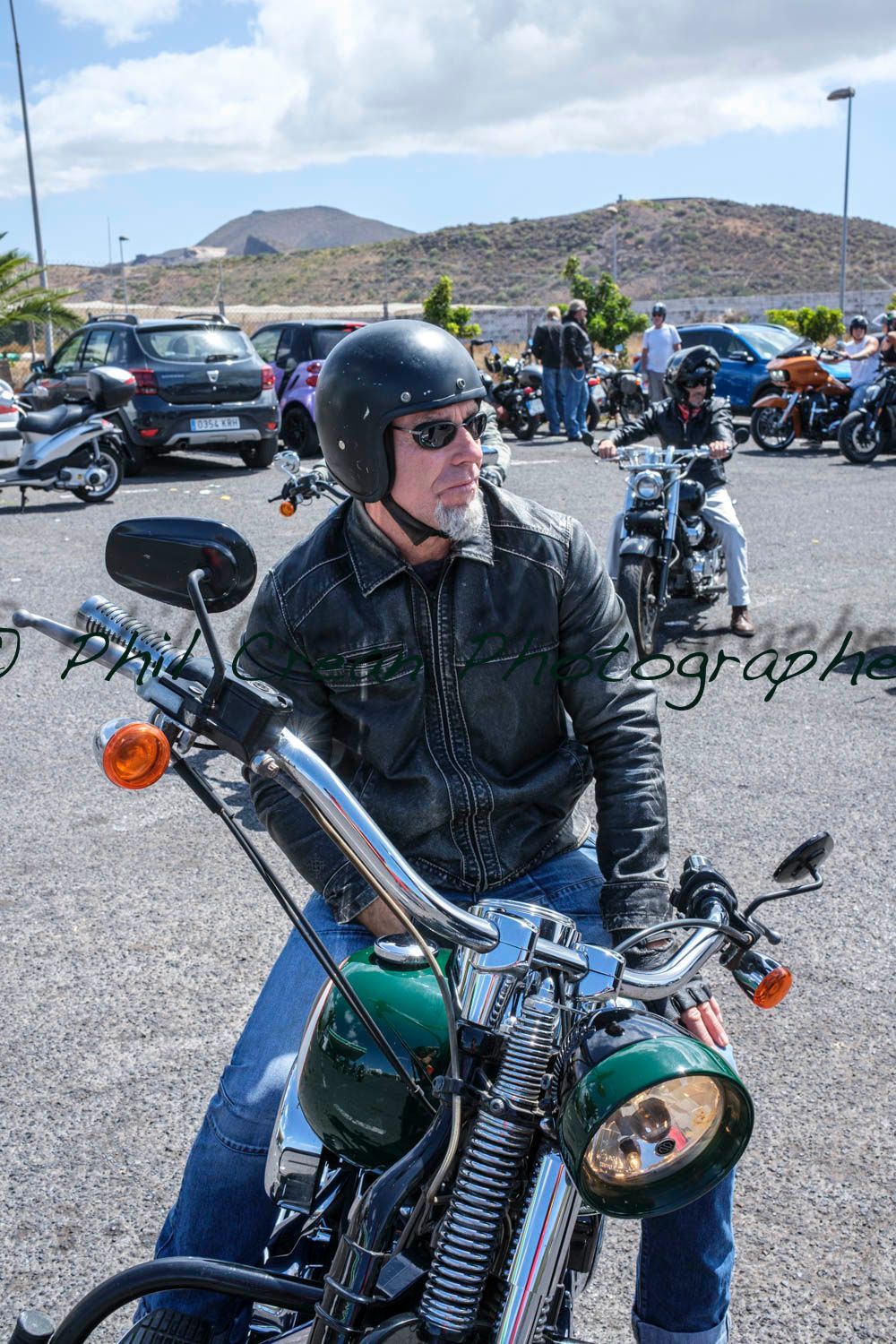 A man is sitting on a motorcycle in a parking lot.