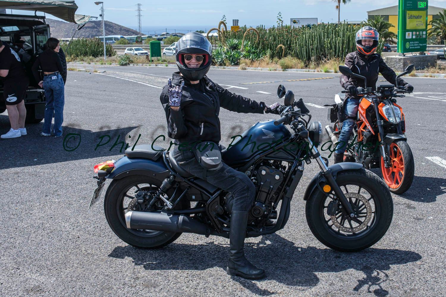 A man is sitting on a motorcycle in a parking lot.