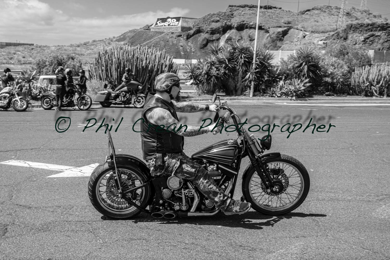 A black and white photo of a man riding a motorcycle