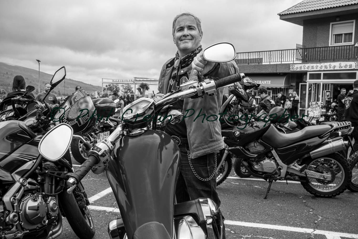 A man is standing next to a motorcycle in a parking lot.