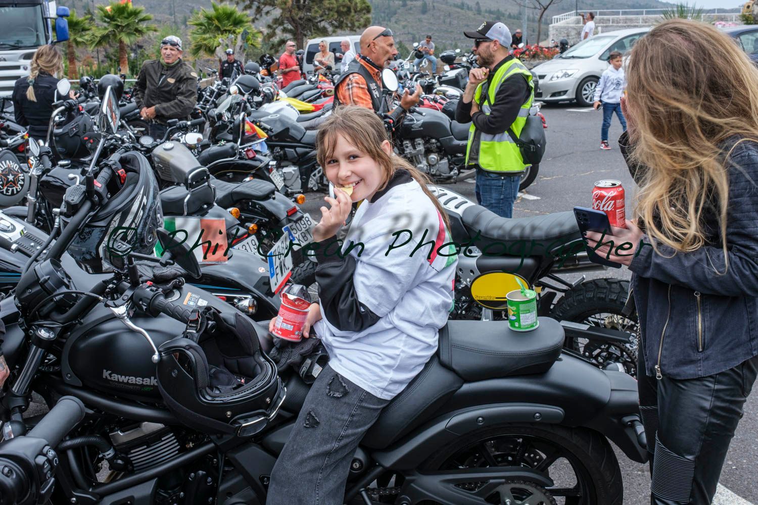 A woman is sitting on a motorcycle in a parking lot.