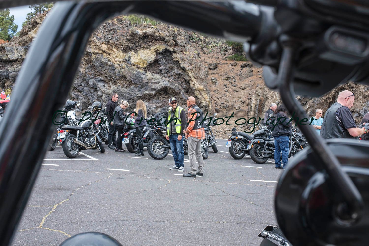 A group of motorcycle riders are standing in a parking lot