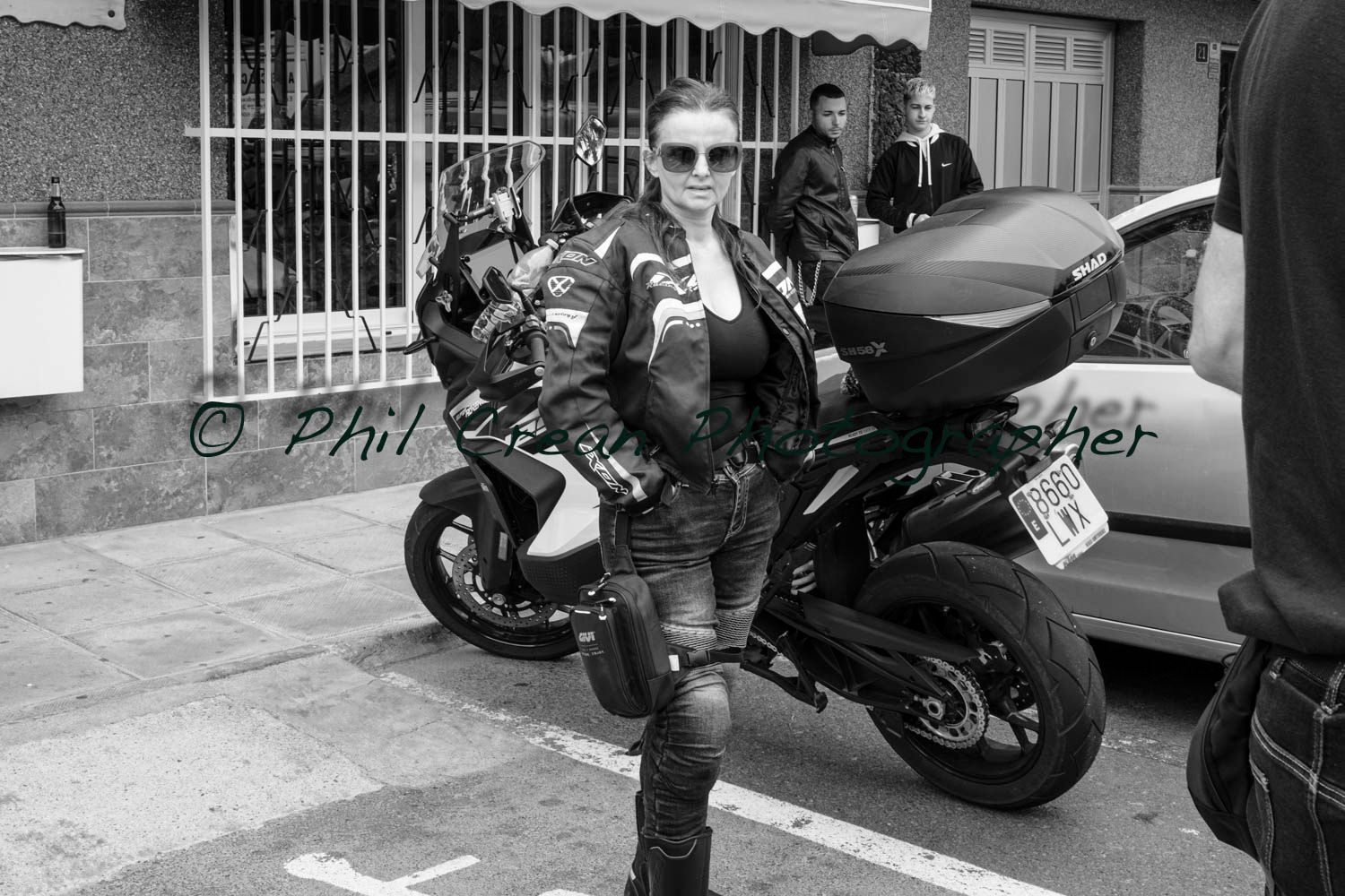 A woman is standing next to a motorcycle in a parking lot.