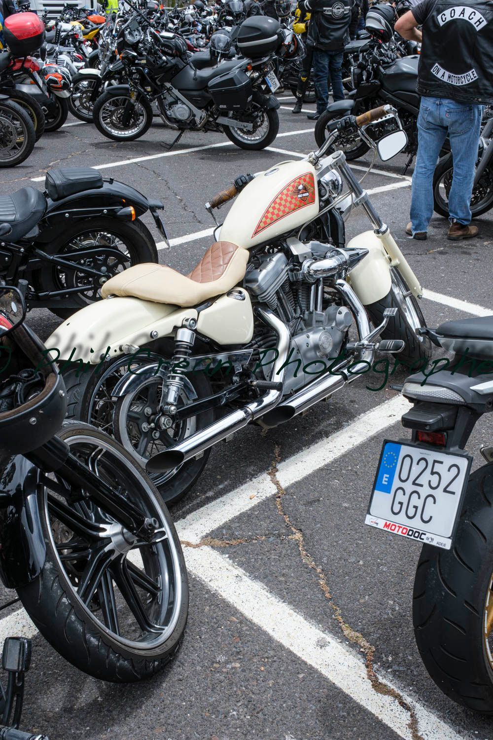 A motorcycle is parked in a parking lot surrounded by other motorcycles.