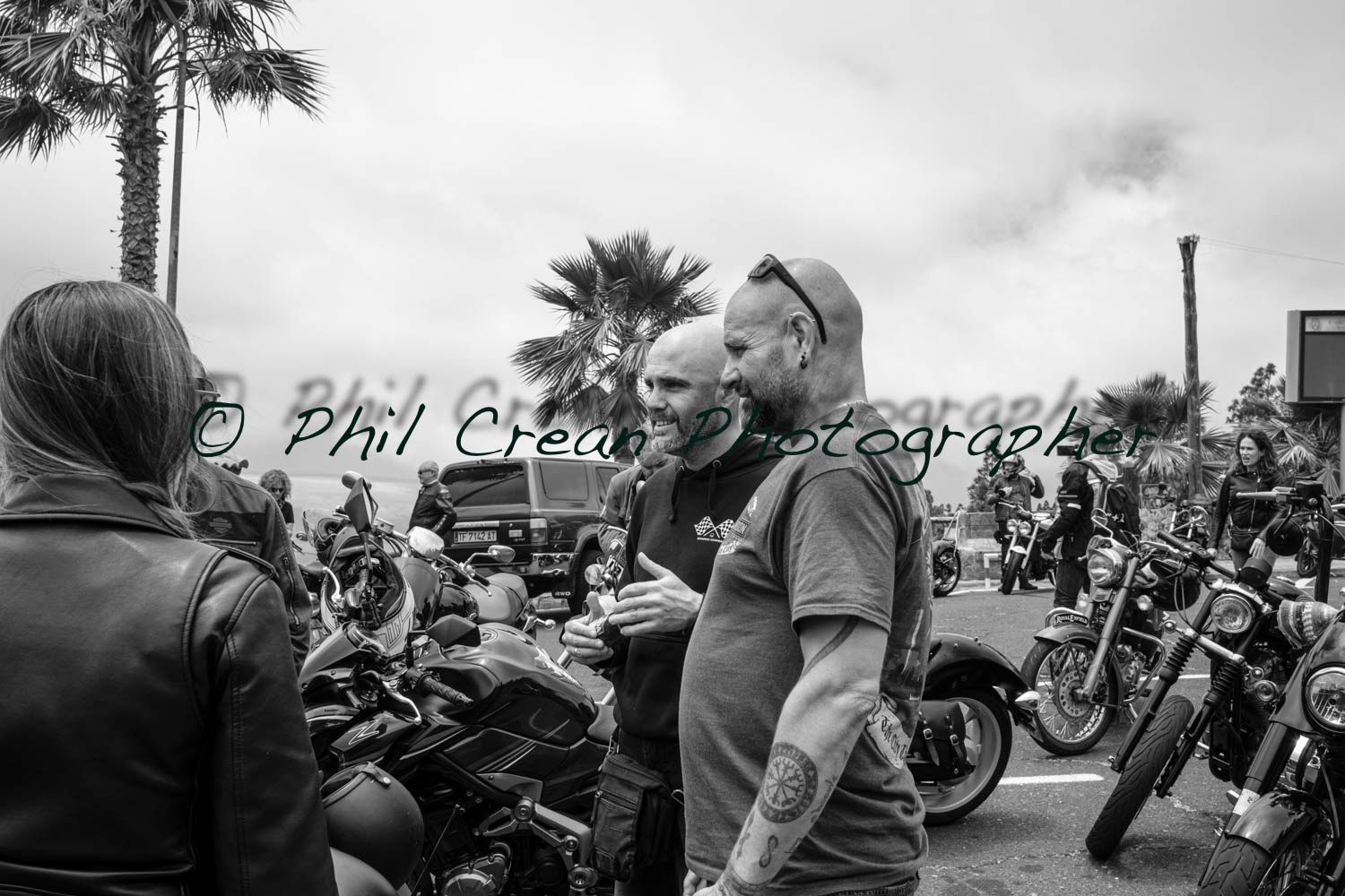 A black and white photo of a group of people standing next to motorcycles.