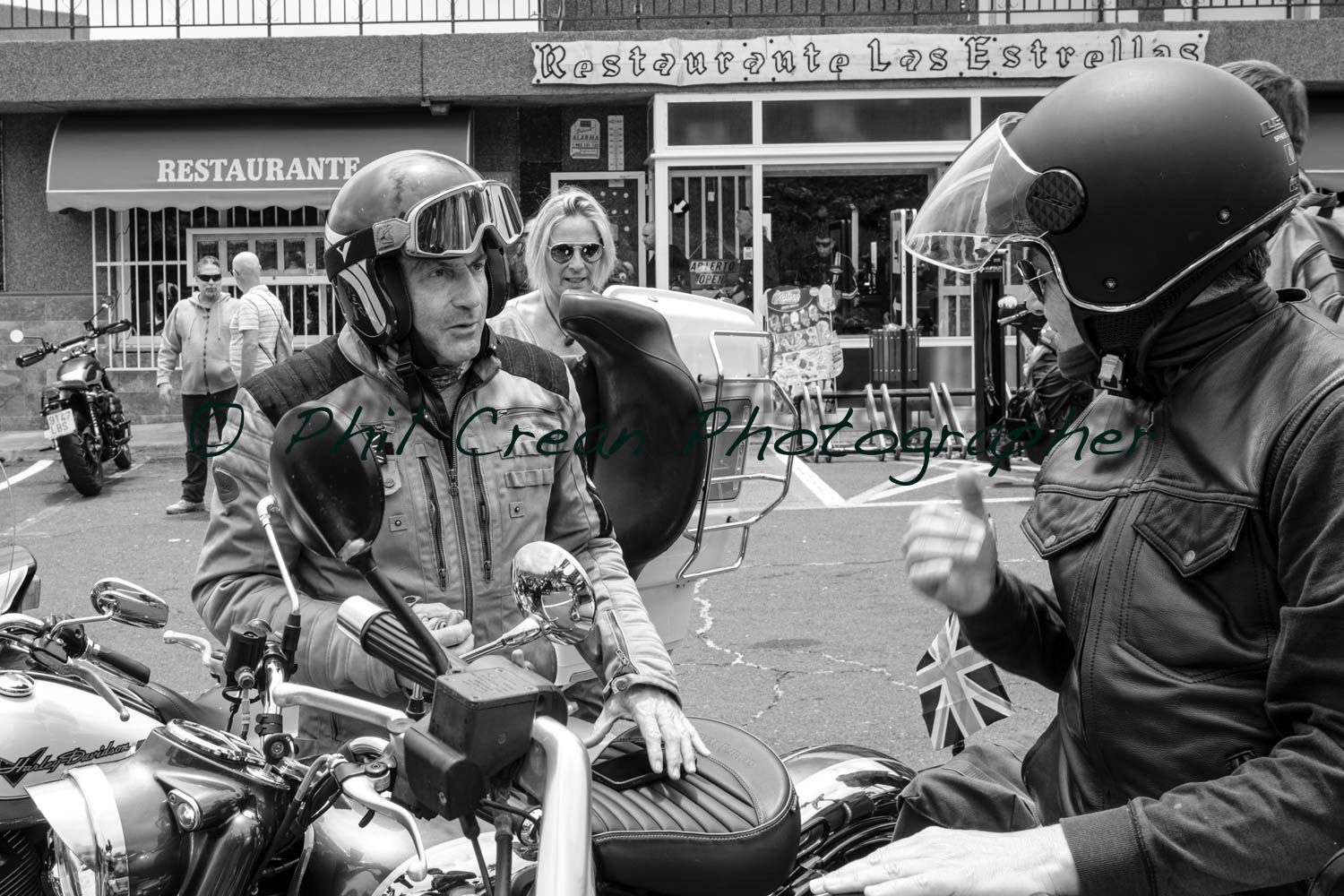 Two men are sitting on motorcycles in front of a restaurant