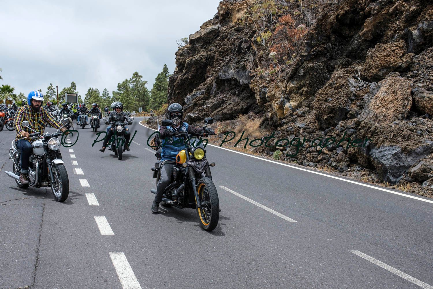A group of people are riding motorcycles down a road.