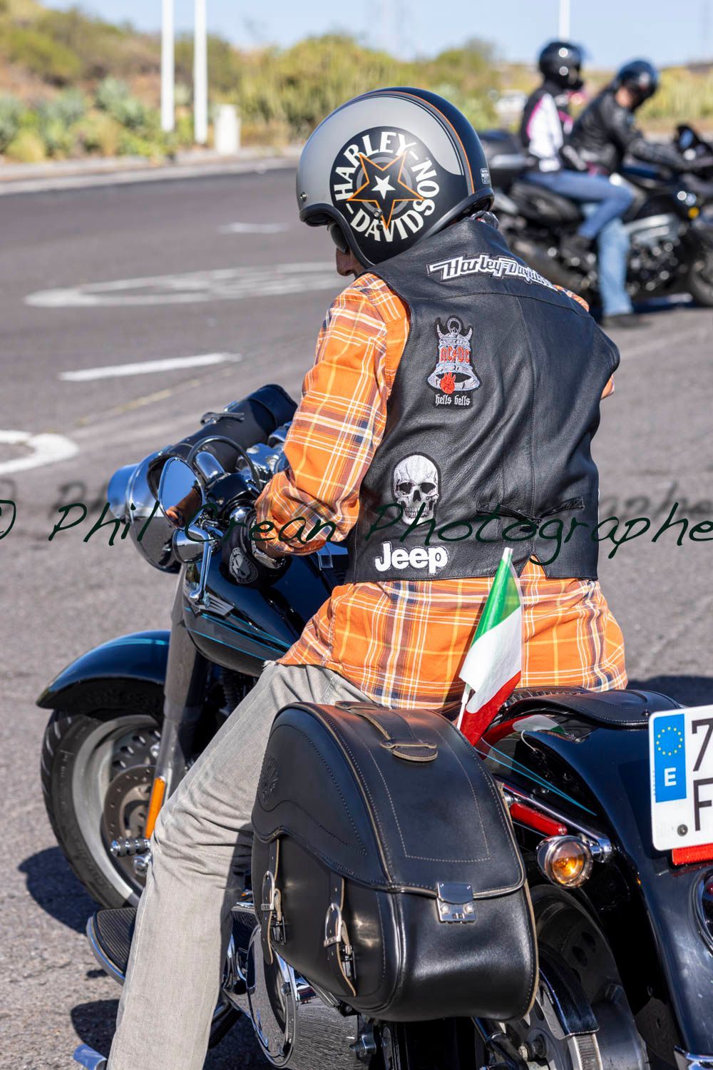 A man wearing a jeep vest is riding a motorcycle