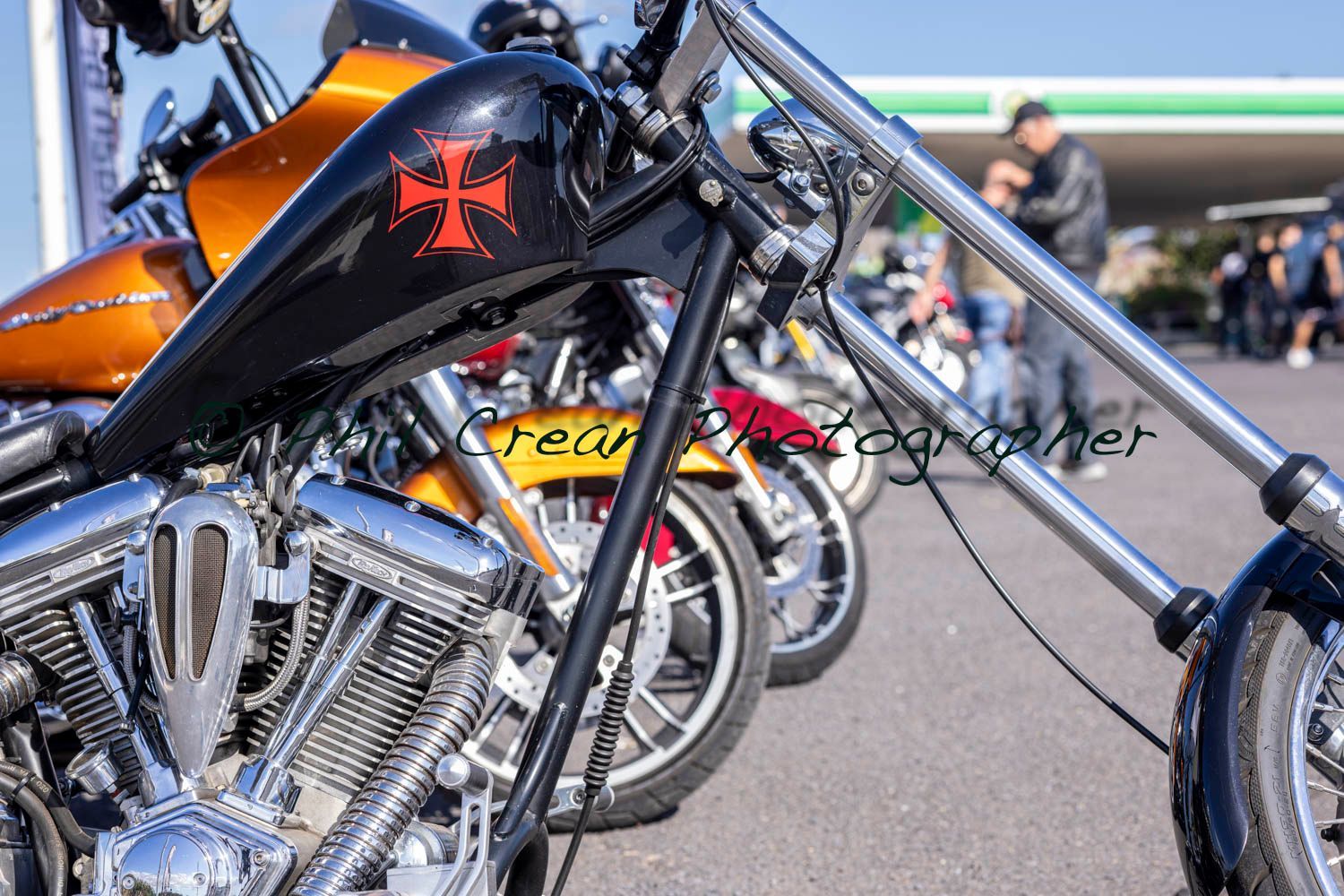 A row of motorcycles are parked in front of a gas station