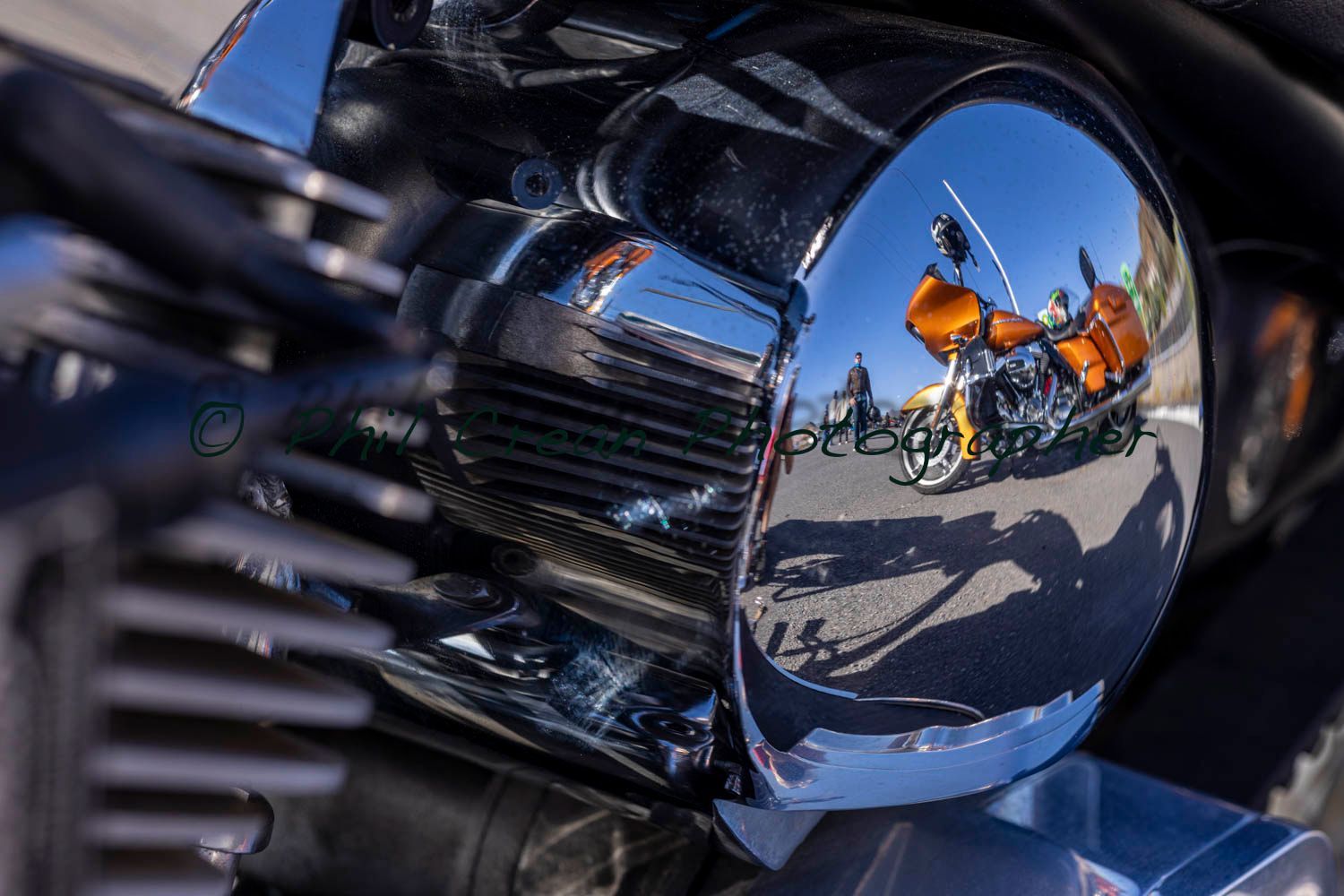 A close up of a motorcycle engine with a reflection of a motorcycle in the mirror.