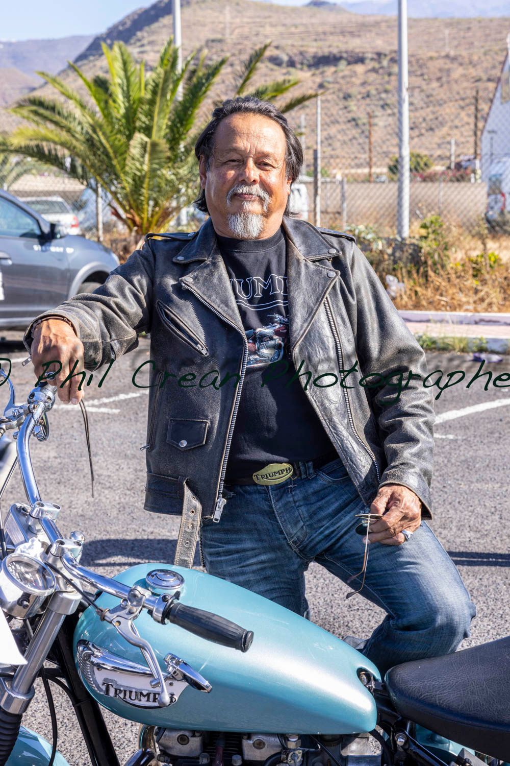 A man in a leather jacket is sitting on a motorcycle.