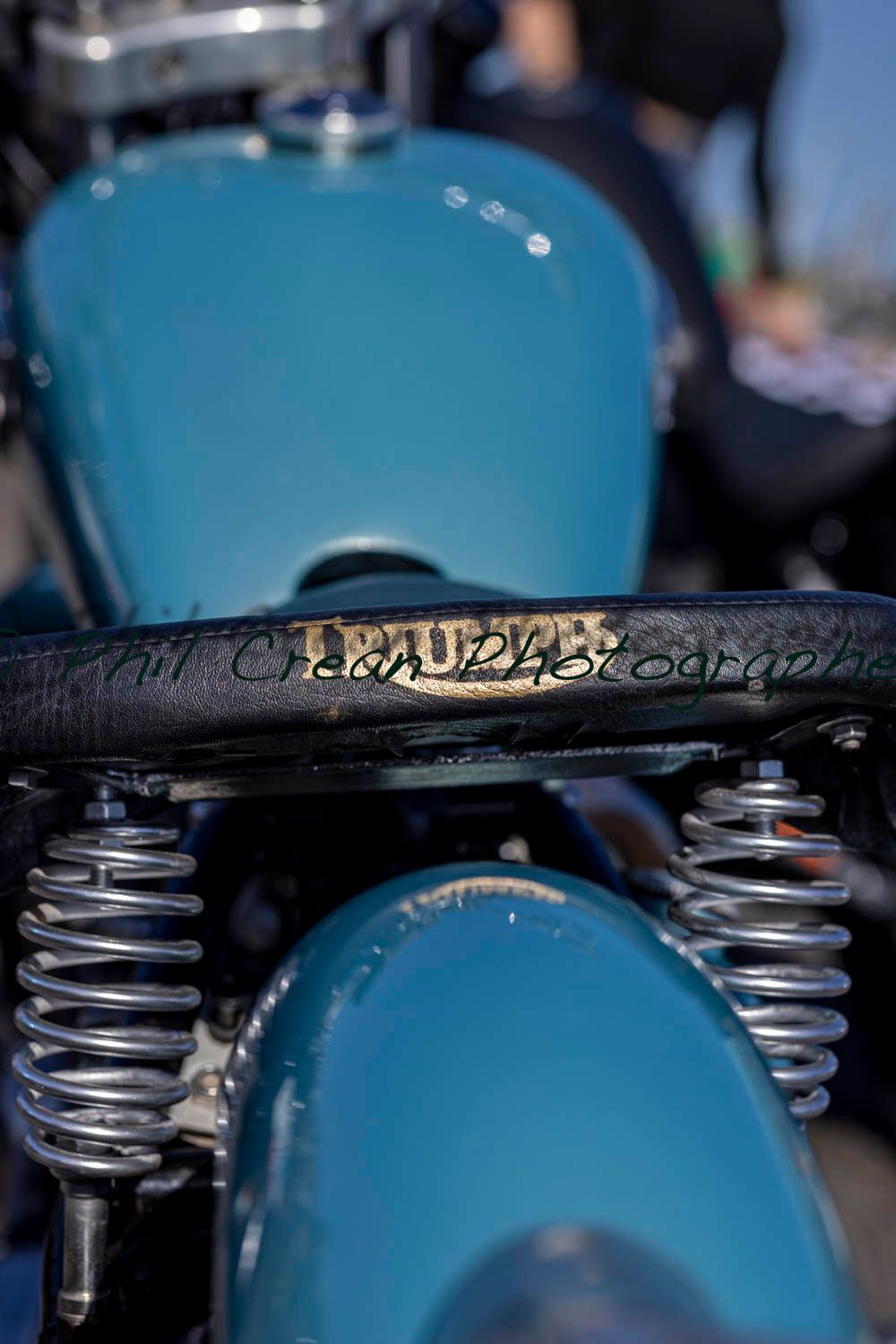 A close up of a motorcycle with a blue tank and springs.