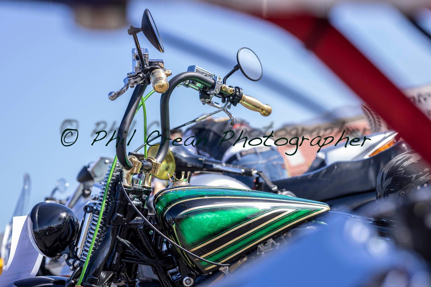 A motorcycle with a green tank is parked next to a car.
