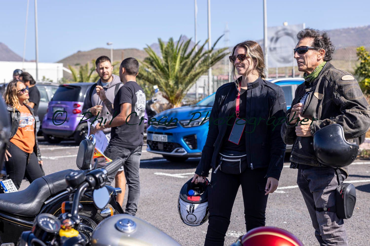 A group of people standing next to motorcycles in a parking lot.