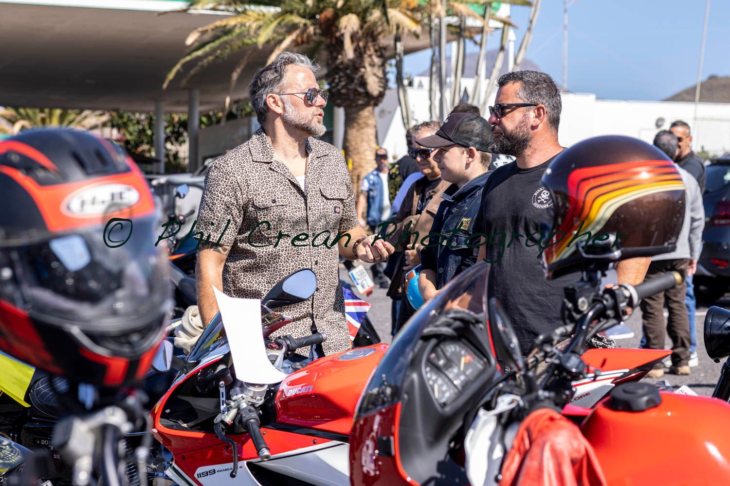 A group of men are standing next to motorcycles and talking to each other.