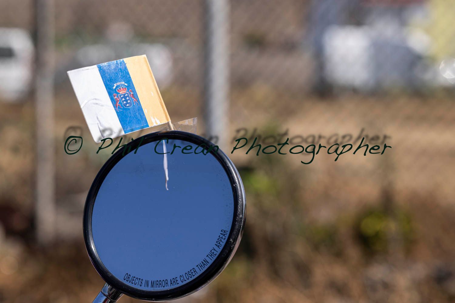 A motorcycle rear view mirror with a small flag on it.