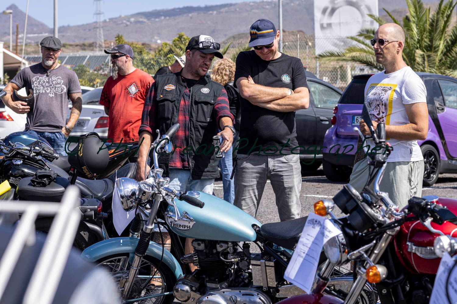 A group of men are standing around motorcycles in a parking lot.