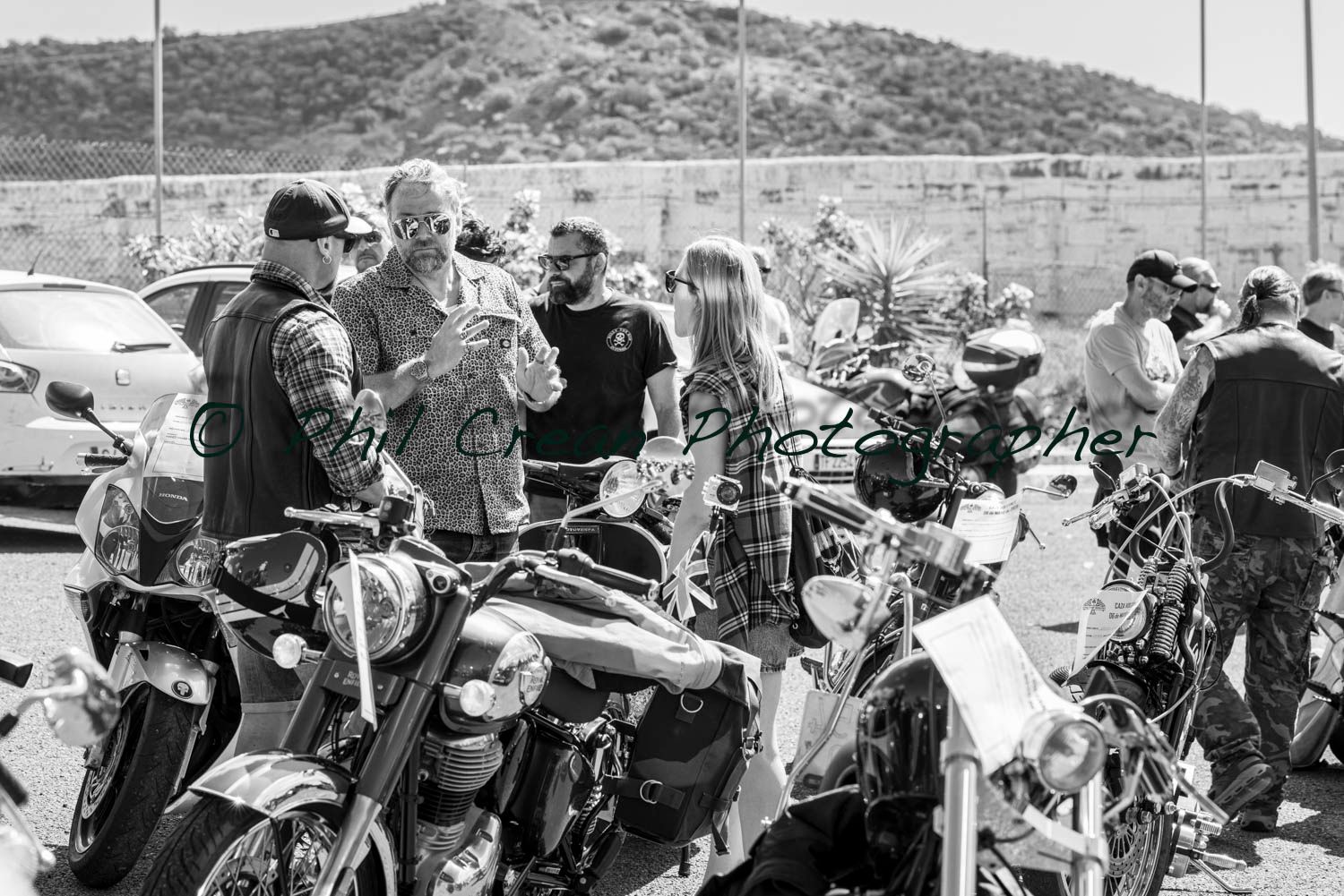 A group of people are standing around motorcycles in a parking lot.