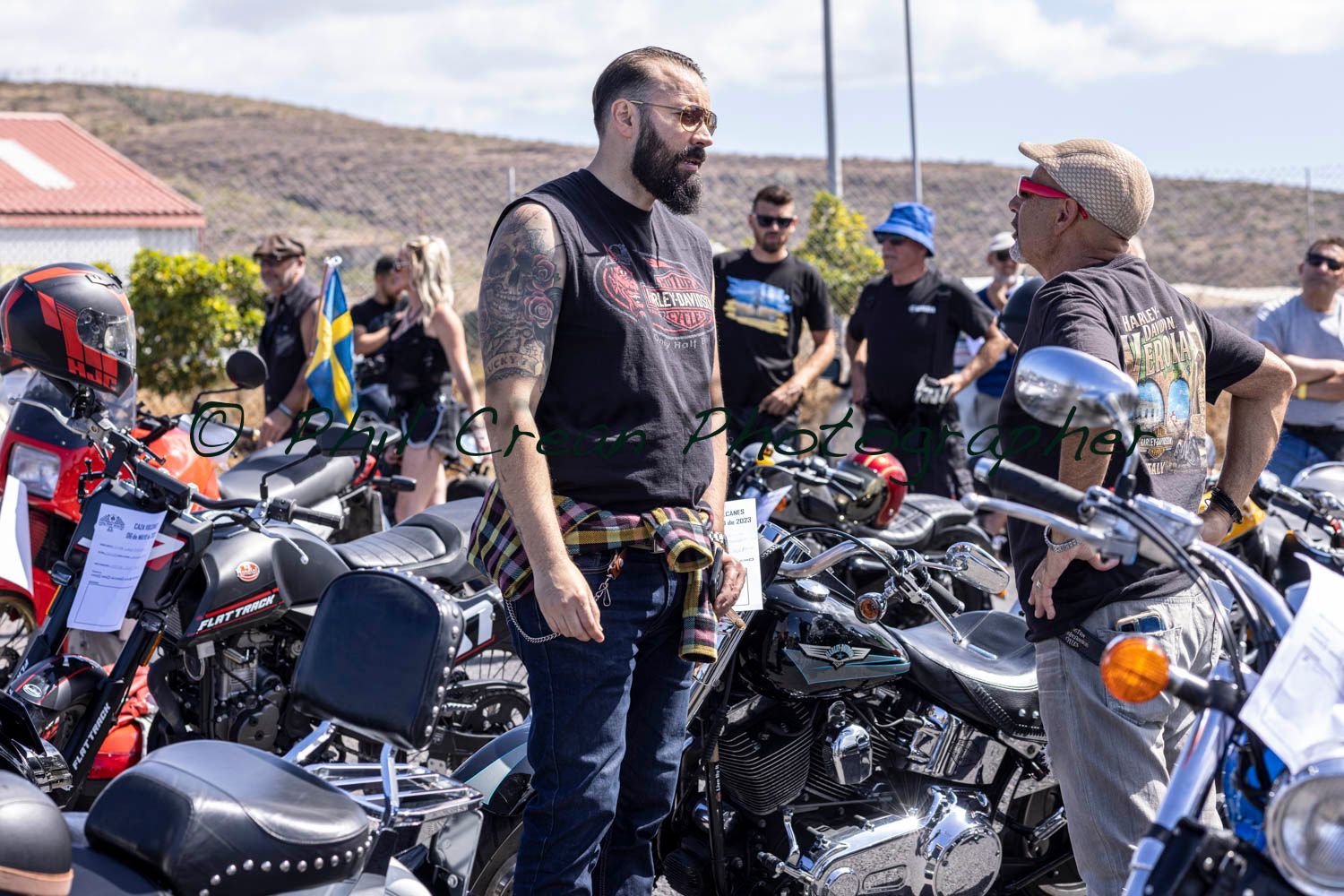 A man with a beard is standing in front of a row of motorcycles.