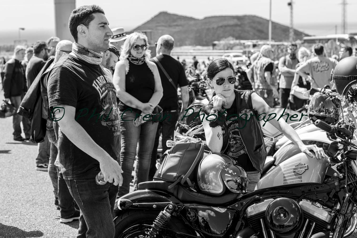 A black and white photo of a group of people standing around motorcycles.