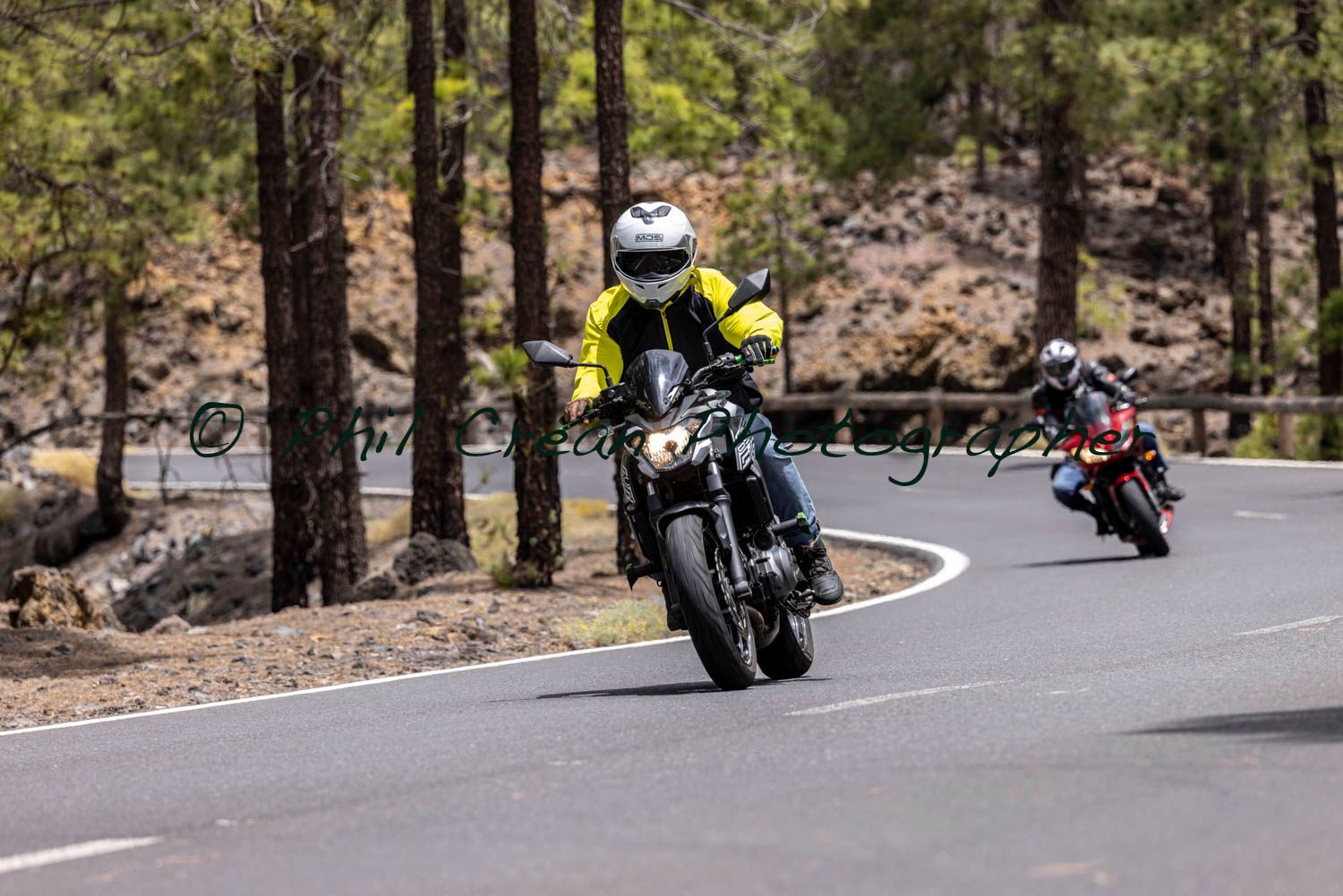 Two people are riding motorcycles down a curvy road.