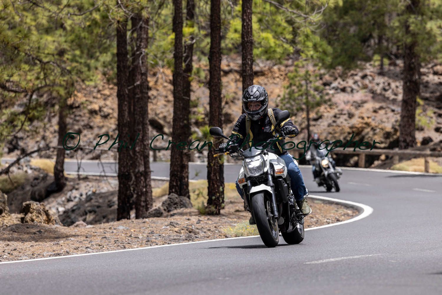 A man is riding a motorcycle down a curvy road.