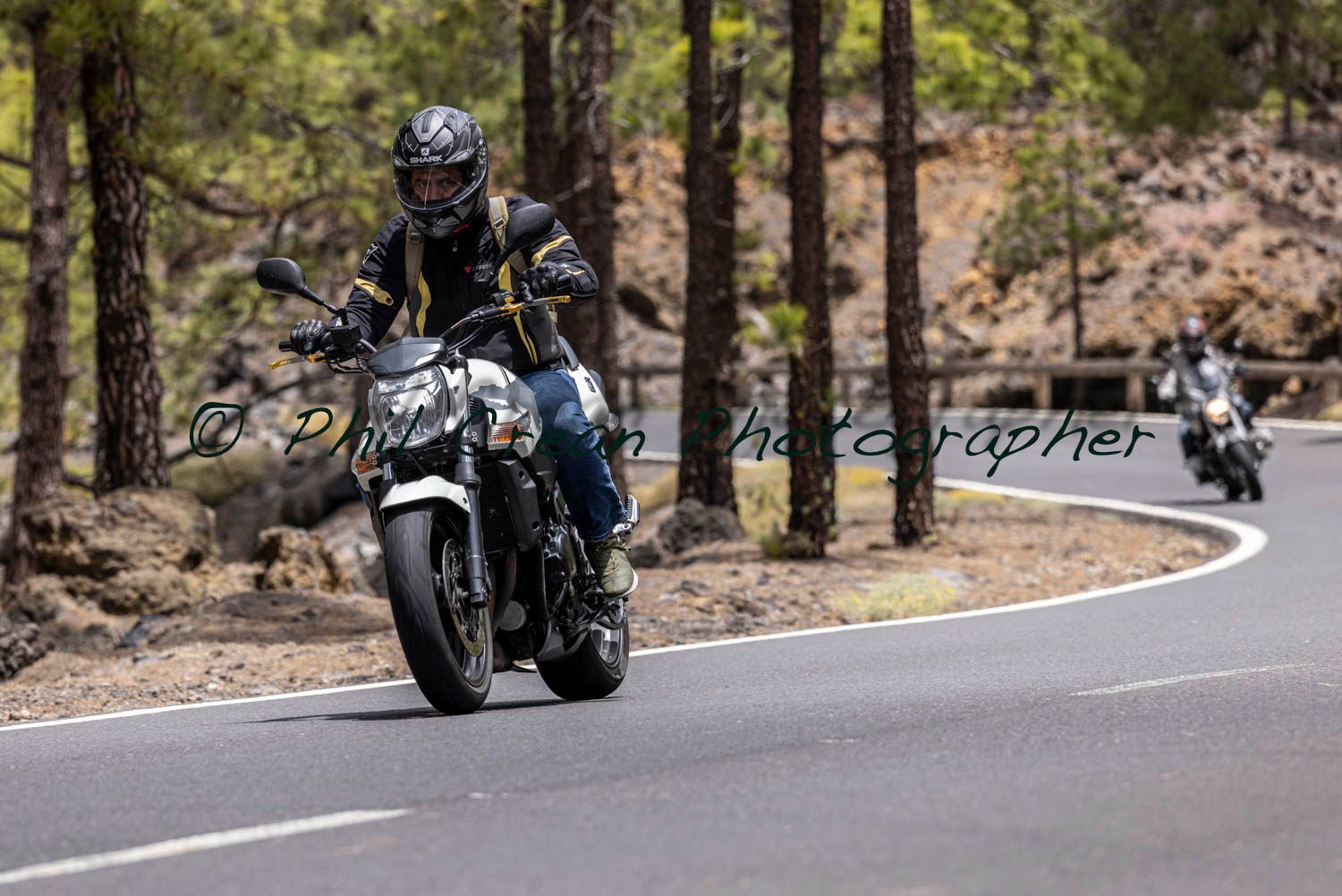 A man is riding a motorcycle down a curvy road.