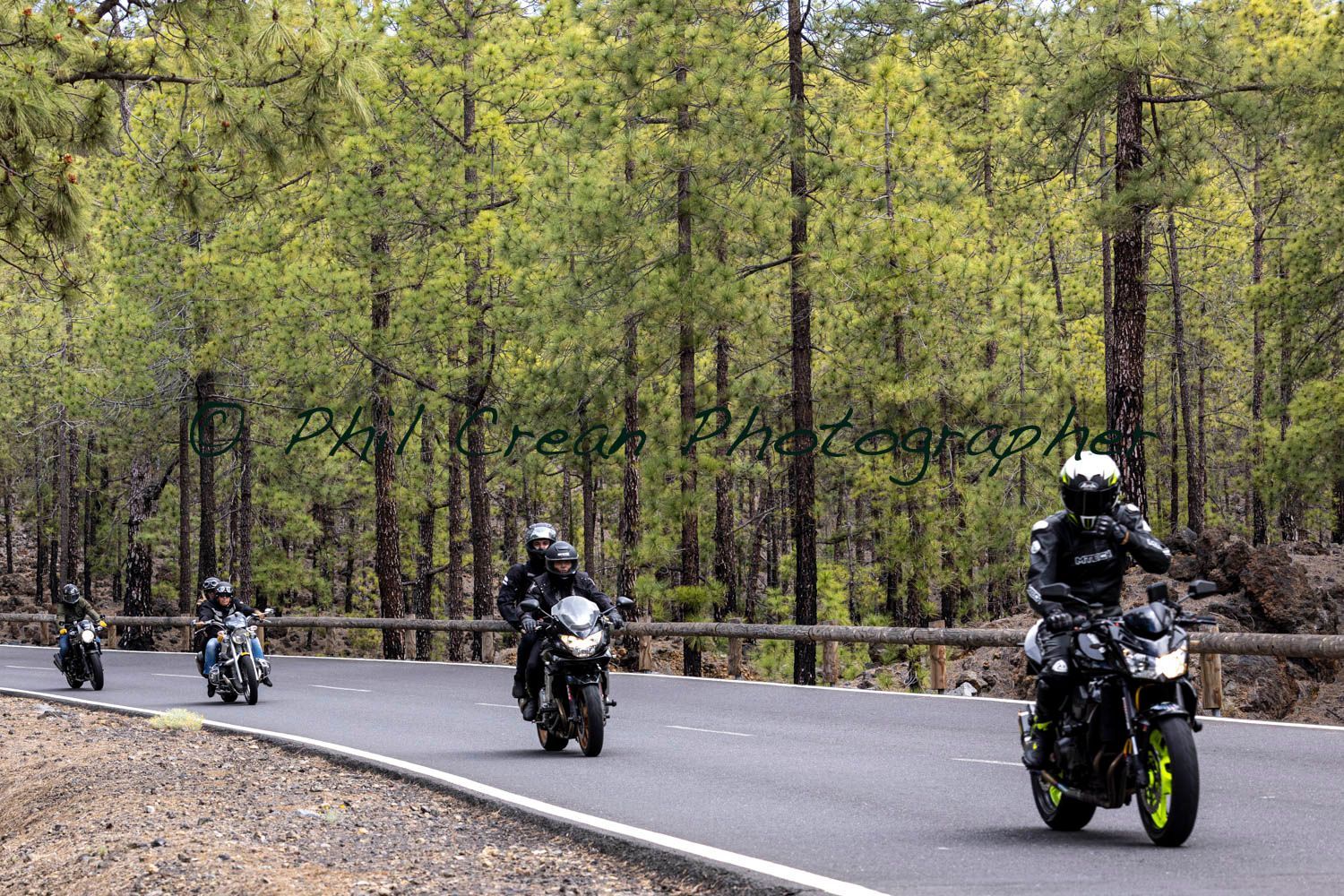 A group of people are riding motorcycles down a road.