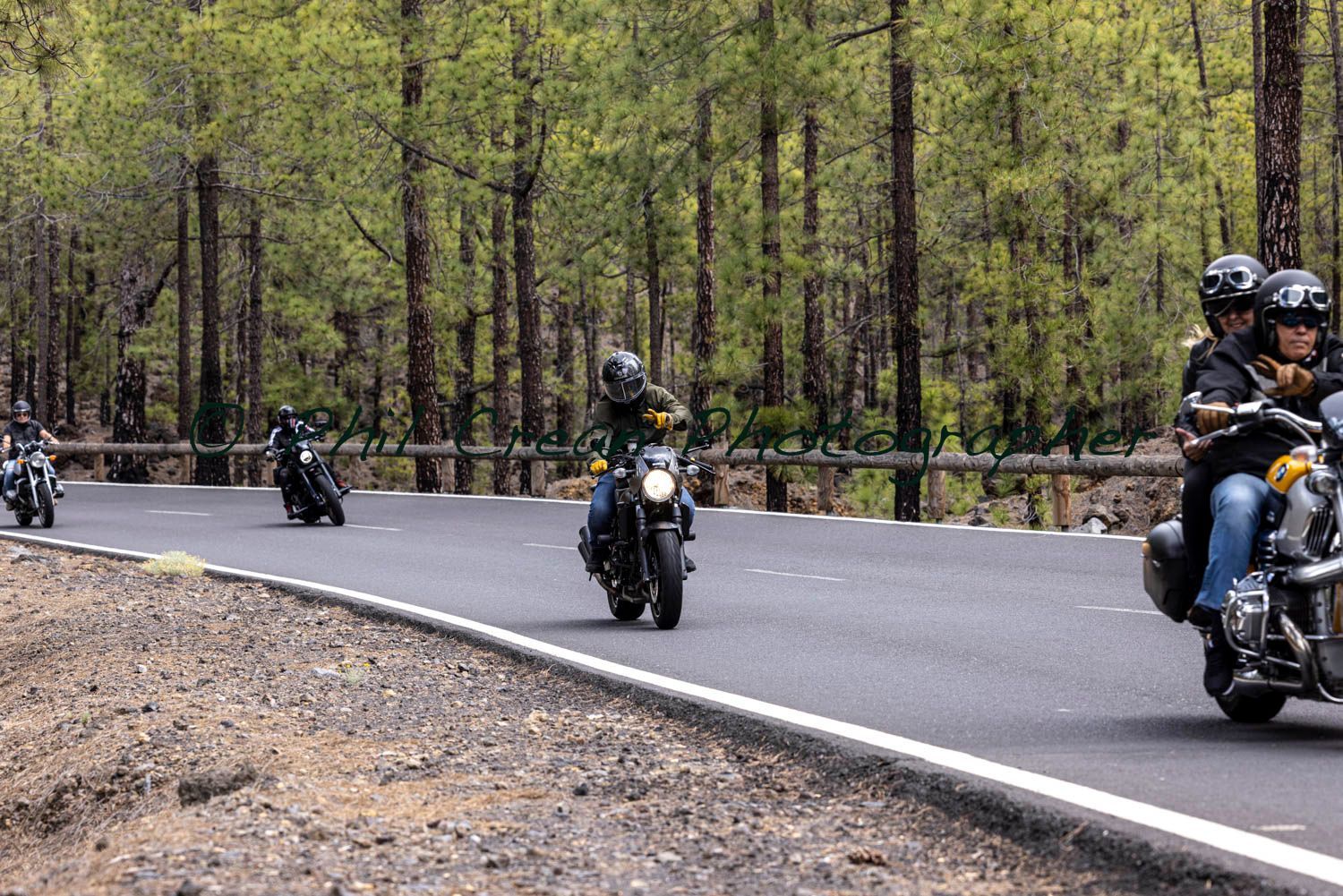 A group of people are riding motorcycles down a road.