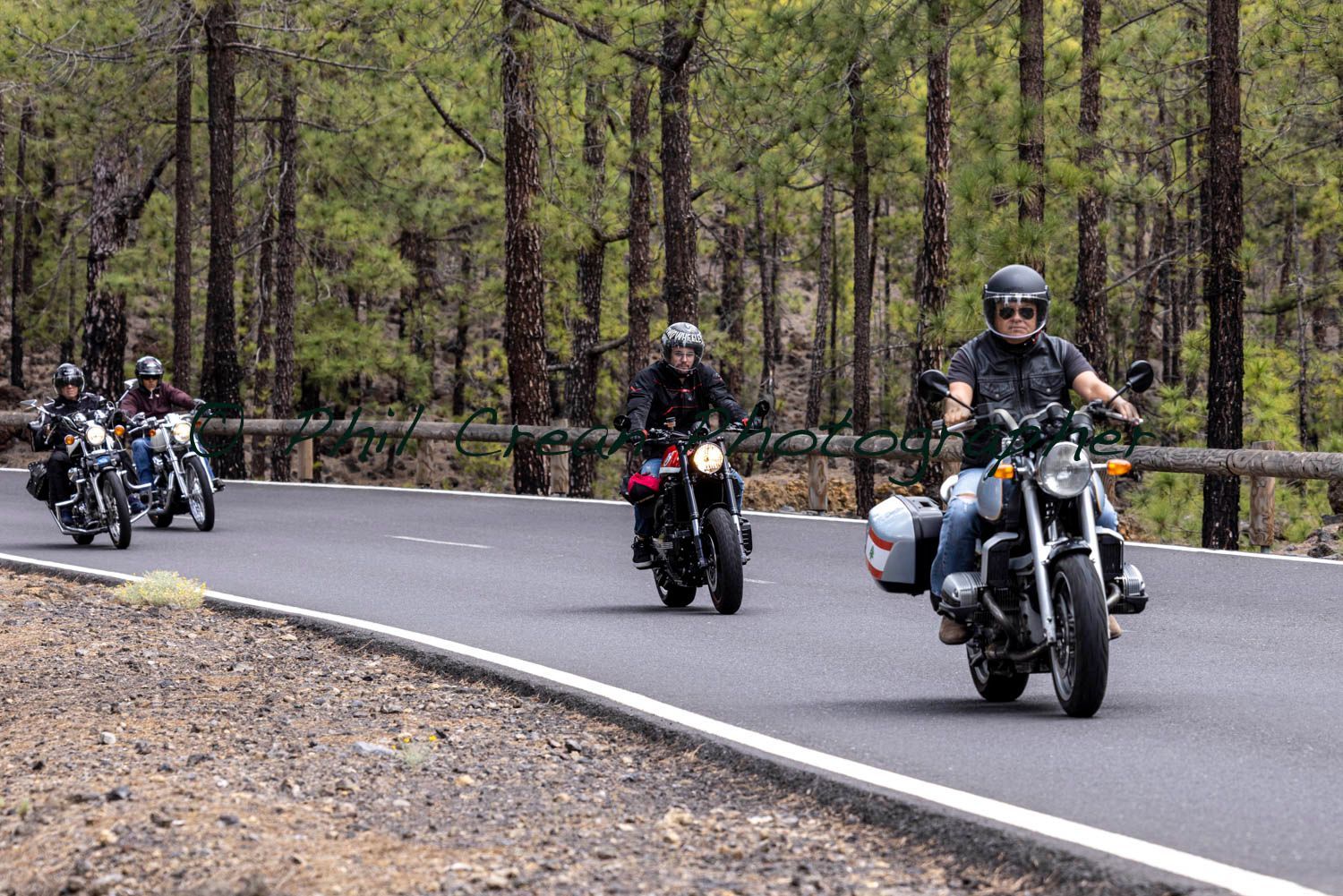 A group of people are riding motorcycles down a road.