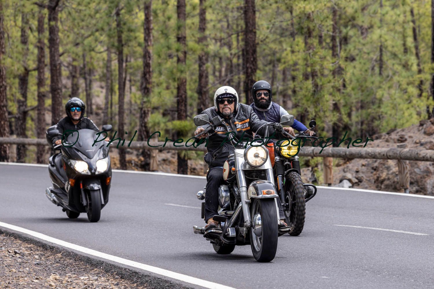 A group of people are riding motorcycles down a road.