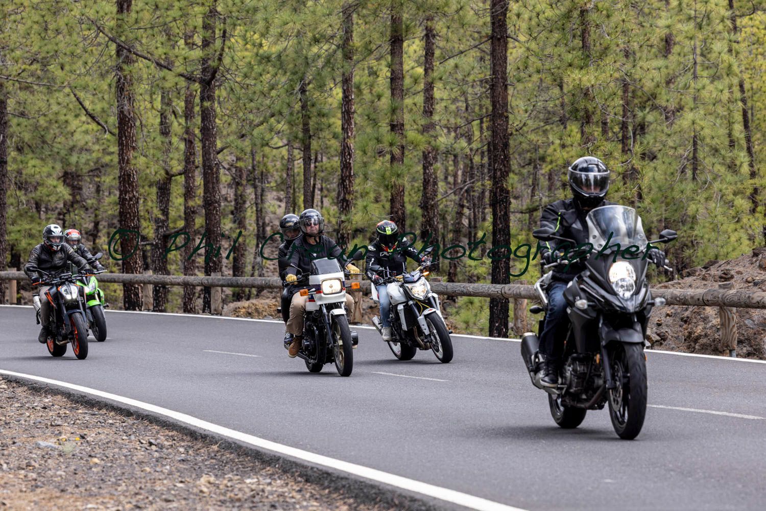 A group of people are riding motorcycles down a road.