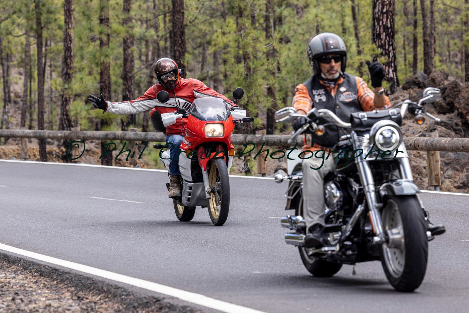Two men are riding motorcycles down a road.