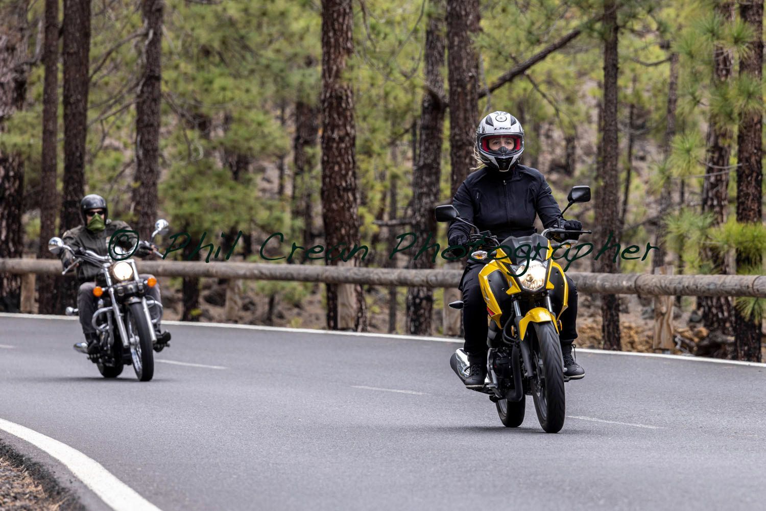 Two people are riding motorcycles down a road.